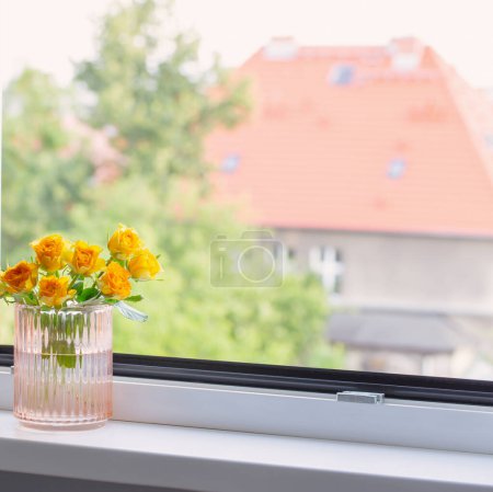 Foto de Rosas amarillas en jarrón de vidrio en alféizar de ventana - Imagen libre de derechos