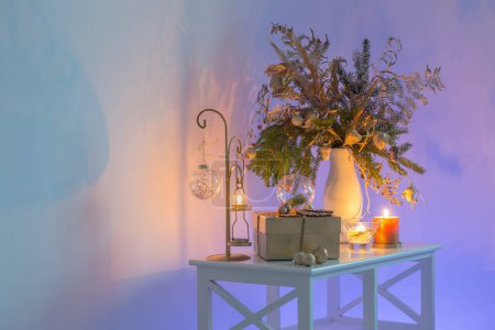 Téléchargez les photos : Bouquet de Noël avec des bougies allumées sur le mur de couleur de fond le soir - en image libre de droit