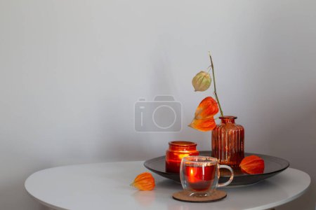 Téléchargez les photos : Nature morte automnale avec des fleurs, des bougies et une tasse de thé sur table blanche - en image libre de droit