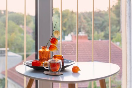 Photo for Autumnal still life with flowers, candles and cup of tea on white table on balcony - Royalty Free Image
