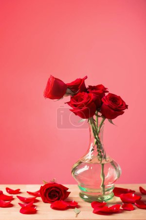 Téléchargez les photos : Roses rouges dans un vase en verre sur fond rouge - en image libre de droit