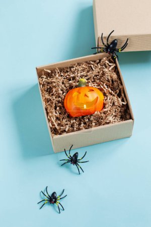 Téléchargez les photos : Citrouille d'Halloween en boîte cadeau avec décor sur fond bleu - en image libre de droit