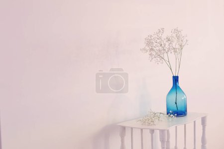 Photo for Gypsophila in blue glass vase on old wooden shelf on white background - Royalty Free Image