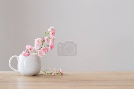 Téléchargez les photos : Poses roses dans une tasse en céramique sur fond blanc - en image libre de droit