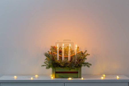 Téléchargez les photos : Décoration de l'avent avec branches de sapin et quatre bougies allumées dans un panier en bois sur fond blanc - en image libre de droit