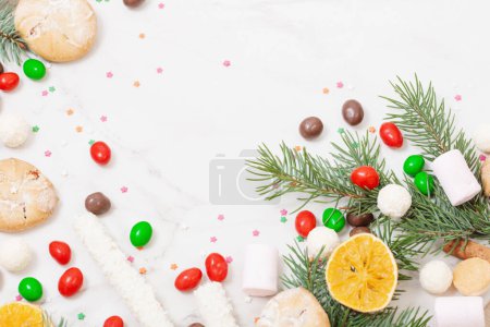 Foto de Caramelos y galletas con ramas de árbol de Navidad sobre fondo de mármol blanco - Imagen libre de derechos