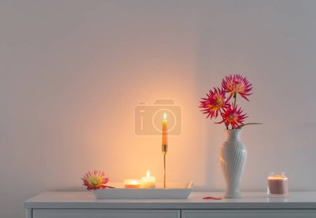 Photo for Beautiful pink dahlia in white vase and burning candles on white background - Royalty Free Image