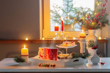 Foto de Decoración de Navidad y tazas rojas con bebida caliente en la cocina - Imagen libre de derechos