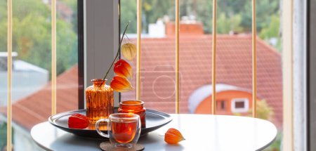 Photo for Autumnal still life with flowers, candles and cup of tea on white table on balcony - Royalty Free Image