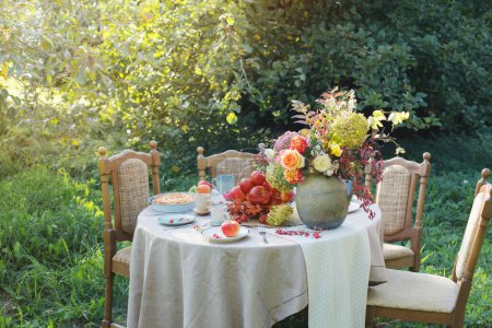Téléchargez les photos : Tarte aux pommes sur la table posée dans le jardin le jour ensoleillé - en image libre de droit