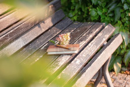 Photo for Leather notebook and pen on old wooden bench in autumn park - Royalty Free Image