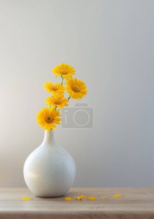 Téléchargez les photos : Gerbera jaune dans un vase moderne sur étagère en bois - en image libre de droit