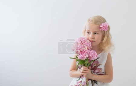 Téléchargez les photos : Belles petites filles blondes avec des fleurs roses sur fond blanc - en image libre de droit