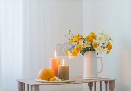 Téléchargez les photos : Fleurs d'automne avec des bougies brûlantes et des citrouilles sur une étagère en bois vintage - en image libre de droit