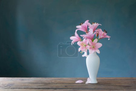 Foto de Lirio rosa en jarrón blanco sobre fondo azul - Imagen libre de derechos