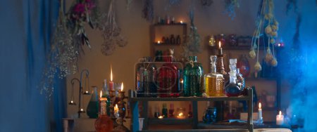Téléchargez les photos : Potions magiques dans la maison de sorcière avec des bougies allumées la nuit - en image libre de droit