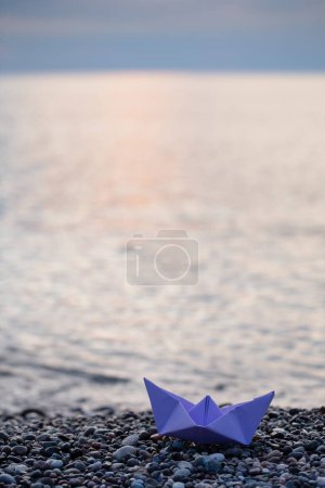 Téléchargez les photos : Bateau en papier au bord de la mer au coucher du soleil - en image libre de droit