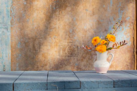Photo for Chrysanthemum flowers in jug on background old wall in sunlight - Royalty Free Image