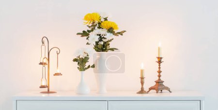 Téléchargez les photos : Chrysanthèmes fleurs dans des vases et des bougies brûlantes à l'intérieur blanc - en image libre de droit