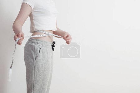 Téléchargez les photos : Femme montre la perte de poids sur fond blanc mur - en image libre de droit