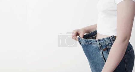 Téléchargez les photos : Fille tirant son gros jeans et montrant la perte de poids - en image libre de droit