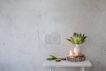 Photo for Lily of the valley in vase with candles on background old white wall - Royalty Free Image