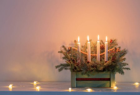 Foto de Adviento decoración con ramas de abeto y cuatro velas encendidas en canasta de madera sobre fondo blanco - Imagen libre de derechos