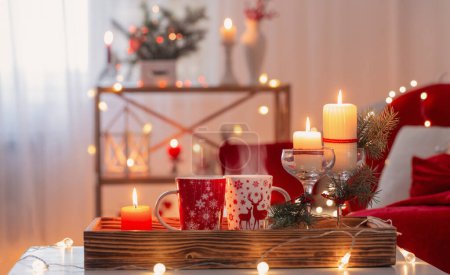 Foto de Taza de bebida caliente con decoraciones navideñas en colores blanco y rojo en casa - Imagen libre de derechos