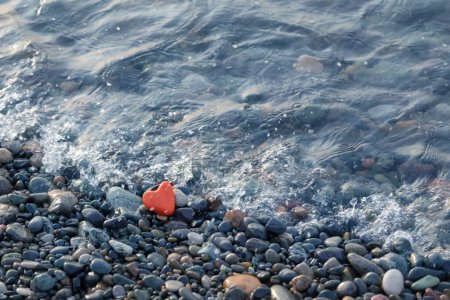Foto de Piedra roja en forma de corazón en la playa por mar - Imagen libre de derechos