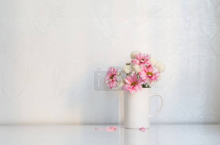 Foto de Crisantemos blancos y rosados en copa vintage sobre fondo blanco - Imagen libre de derechos