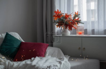 Téléchargez les photos : Chambre moderne blanche avec bouquet d'automne et oreillers sur canapé - en image libre de droit