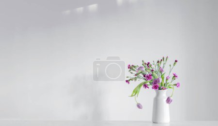 Foto de Flores de color púrpura primavera en el estante blanco en la pared de fondo - Imagen libre de derechos
