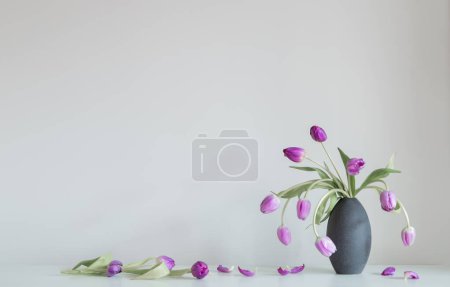 Foto de Tulipanes morados en estante blanco en la pared de fondo - Imagen libre de derechos
