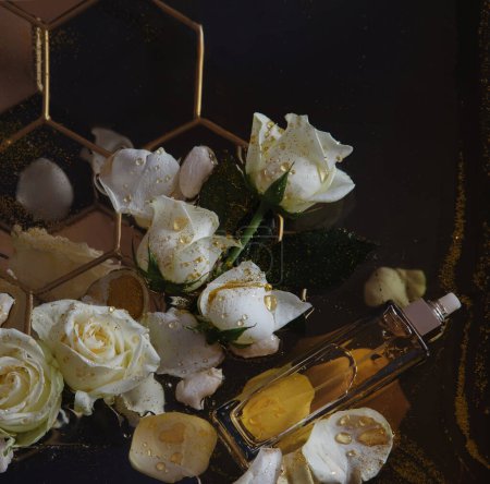 Foto de Frasco de perfume con aroma a miel y rosas sobre un fondo oscuro - Imagen libre de derechos