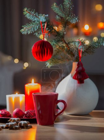 Foto de Bebida caliente en taza roja con decoraciones navideñas en casa - Imagen libre de derechos