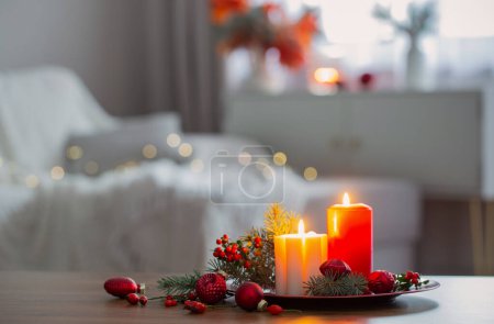 Photo for Burning candles with christmas branches on table in white interior - Royalty Free Image