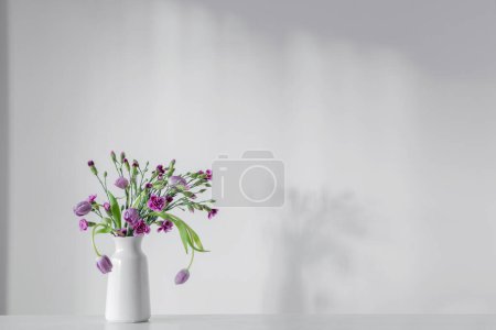 Foto de Flores de color púrpura primavera en el estante blanco en la pared de fondo - Imagen libre de derechos