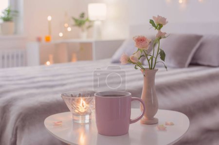 Téléchargez les photos : Tasse rose de café et roses dans un vase sur la table dans la chambre - en image libre de droit
