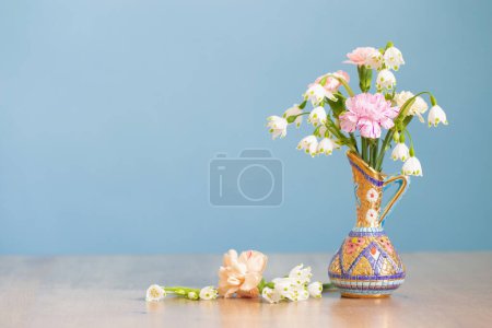 Téléchargez les photos : Fleurs en cruche vintage sur table en bois sur fond bleu - en image libre de droit