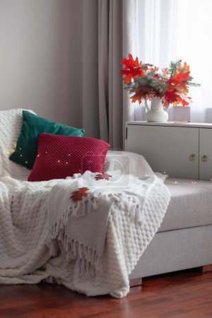 Foto de Habitación moderna blanca con ramo de otoño y almohadas en el sofá - Imagen libre de derechos