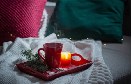Photo for Red cup of tea on wooden tray with fir branches on sofa - Royalty Free Image