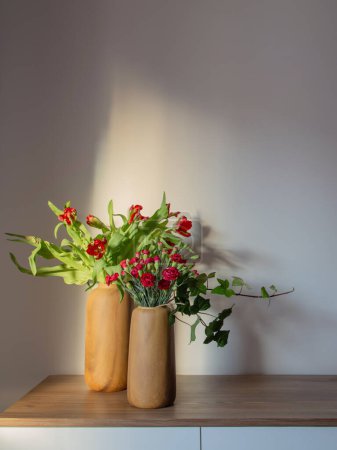 Photo for Red carnations and tulips in modern vases on background gray wall - Royalty Free Image