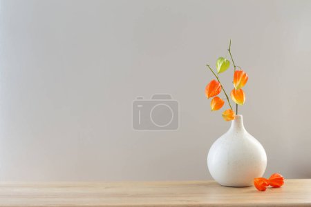 Photo for Physalis in modern vase on wooden table - Royalty Free Image