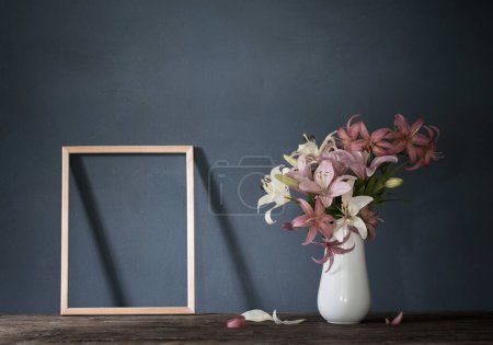 Photo for Flowers in vase and wooden frame on background dark wall - Royalty Free Image