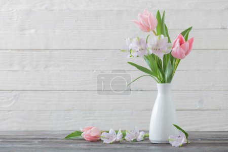 Téléchargez les photos : Fleurs de printemps en vase blanc sur fond bois blanc - en image libre de droit