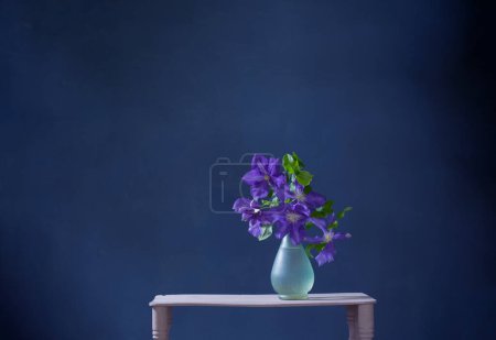 Téléchargez les photos : Fleurs clematis dans un vase en verre sur étagère vintage en bois - en image libre de droit