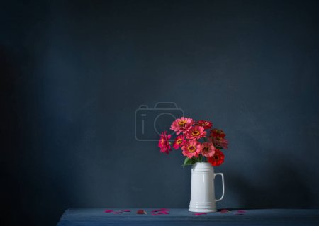 Téléchargez les photos : Fleurs roses en cruche blanche sur fond bleu foncé - en image libre de droit