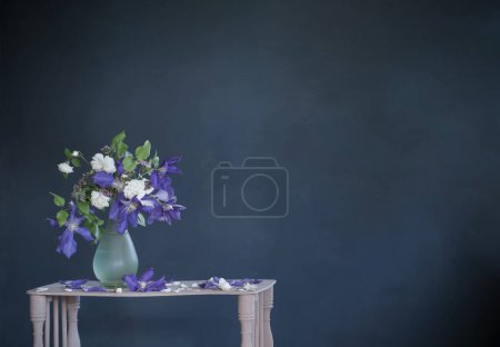 Téléchargez les photos : Fleurs clematis dans un vase en verre sur étagère vintage en bois - en image libre de droit