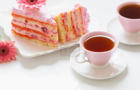 Photo for Two cups of tea with pink cake on white table - Royalty Free Image
