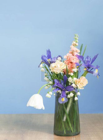Foto de Flores de primavera en jarrón de vidrio sobre fondo azul - Imagen libre de derechos